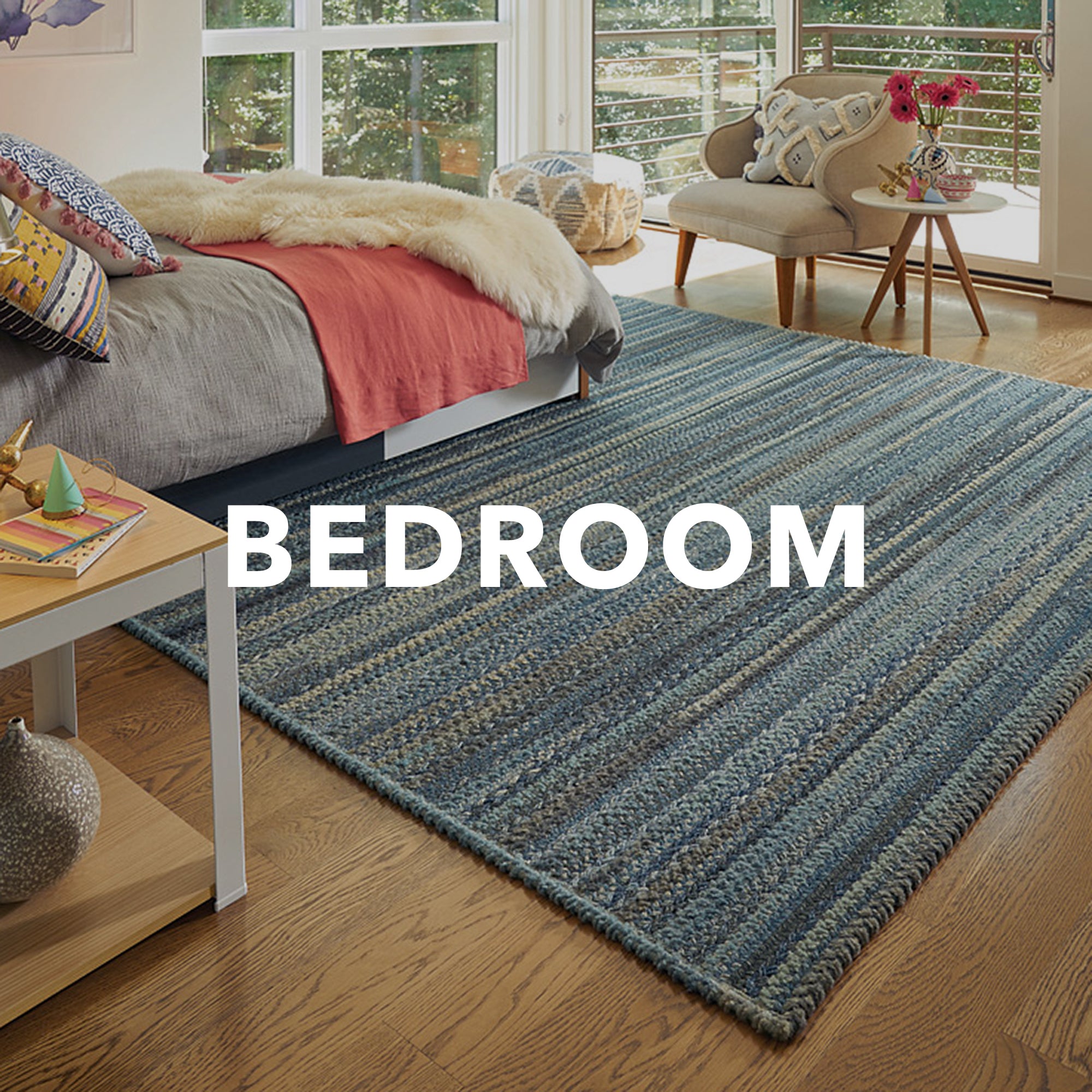 bayview slate blue braided rug in bedroom scene with the word "bedroom" written across in white